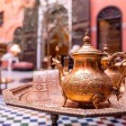 Ceainic tradițional din cupru decorat cu pahare pe masa unui local din Medina din Fes, Maroc