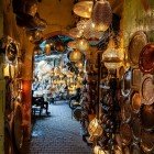 Shopping în Medina din Marrakech printre străduțele înguste ale souk-ului pentru obiecte artizanale locale din cupru și fier forjat