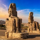 Colosii din Memnon, statui uriașe din piatră construite de faraonul Amenhotep III acum peste 3400 de ani în necropola Tebei, pe malul opus al orașului Luxor