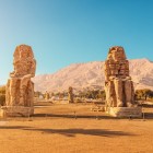 Vedere a necropolei tebane de pe malul opus al Nilului față de orașul Luxor, cu Colosii din Memnon, construiți acum peste 3400 de ani de faraonul Amenhotep III